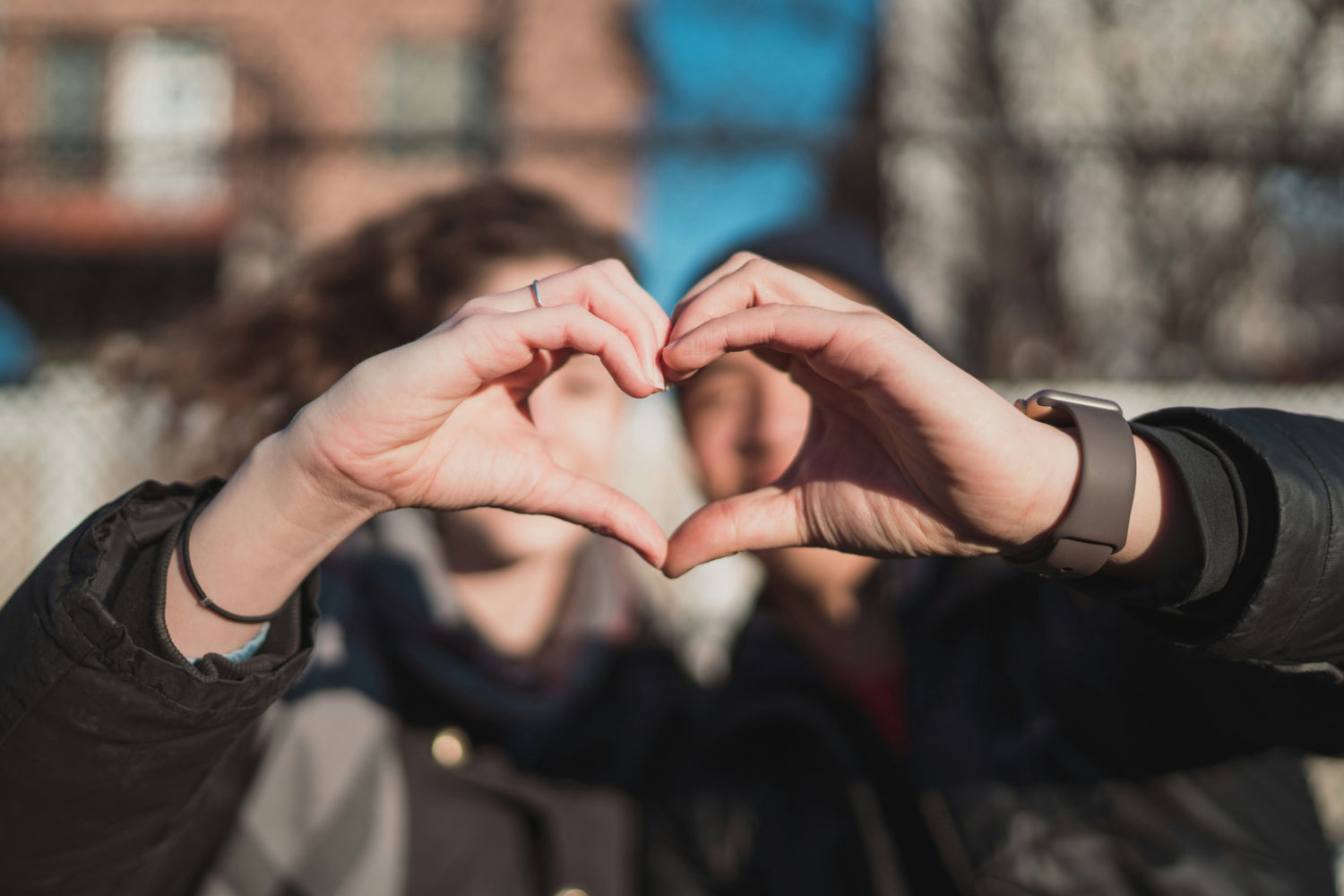 Two people forming a heart shape with their hands, symbolizing love and connection, potential concept for Valentine's gifts for her.