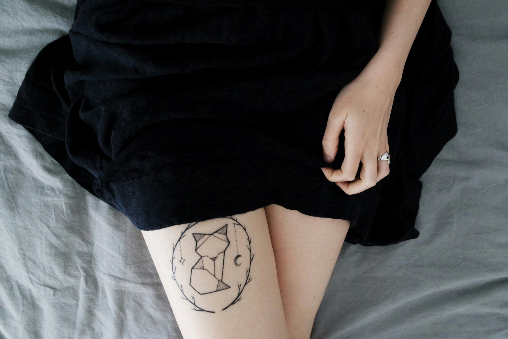 Person lying with a geometric tattoo on their thigh, indicative that IPL hair removal should not be used on tattoos.