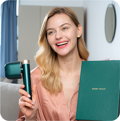 Smiling woman holding JOVS Venus II IPL hair removal device alongside its elegant green packaging.